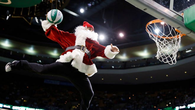 A performer in a Santa Claus costume makes a trick dunk during a timeout in the fourth quarter of an NBA basketball game between the Boston Celtics and the Minnesota Timberwolves in Boston, Monday, Dec. 16, 2013.