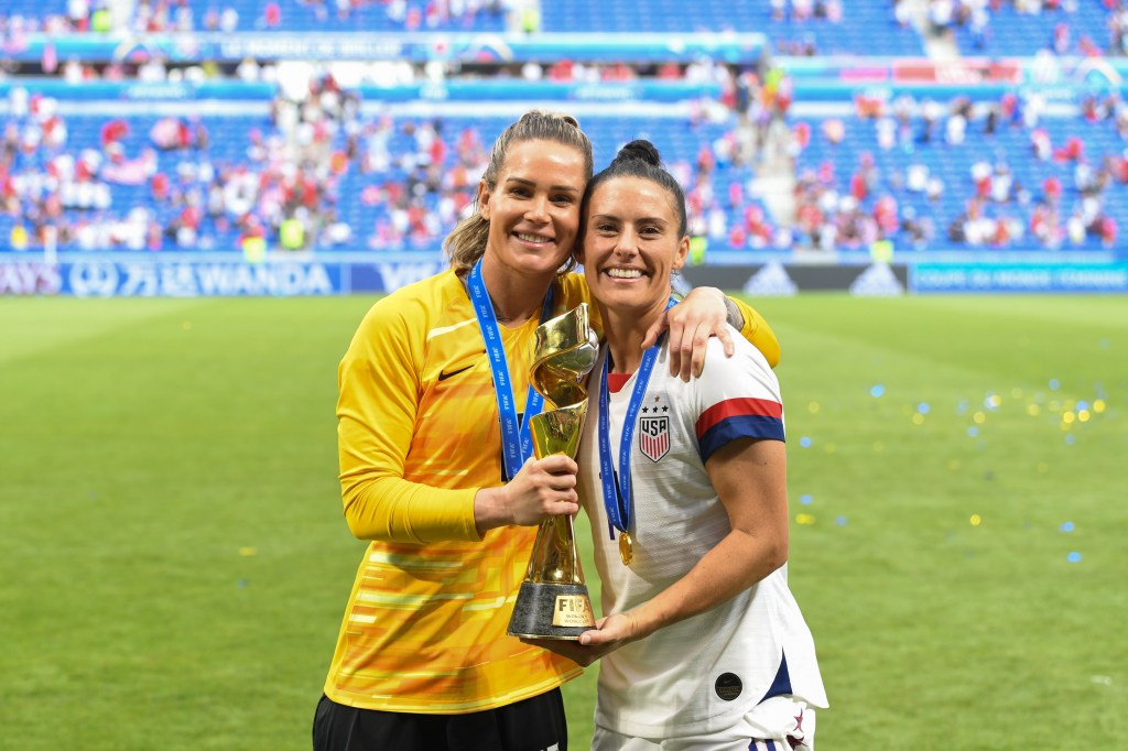 Ashlyn Harris #18 and teammate Ali Krieger #11 pose with the World Cup after the 2019 FIFA Women's World Cup France final match between the Netherlands and the United States at Stade de Lyon on July 07, 2019 in Lyon, France.