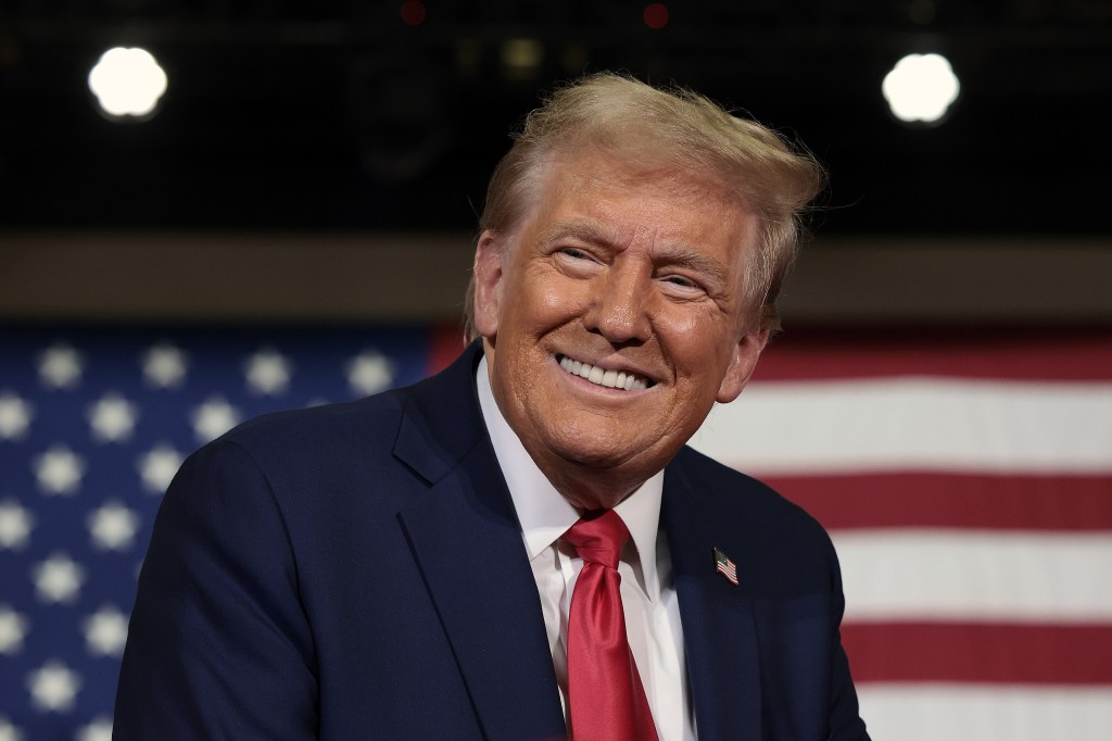 Donald trump poses in front of a flag