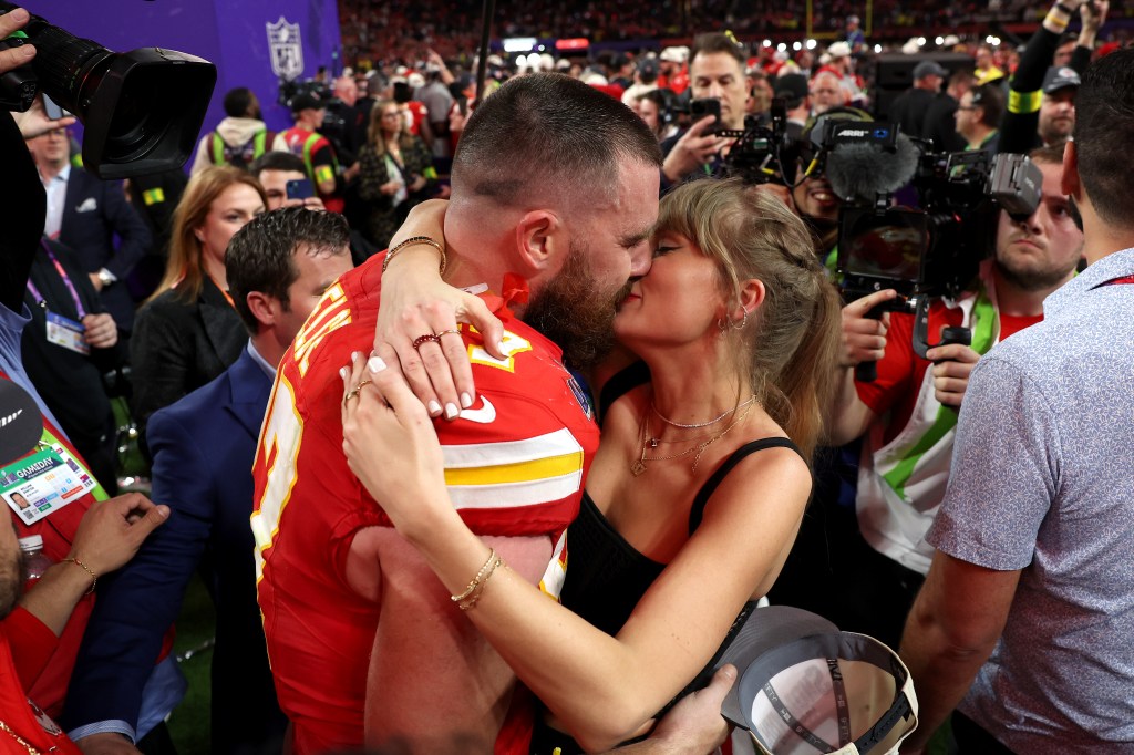 Taylor Swift and Travis Kelce kissing at a football game.