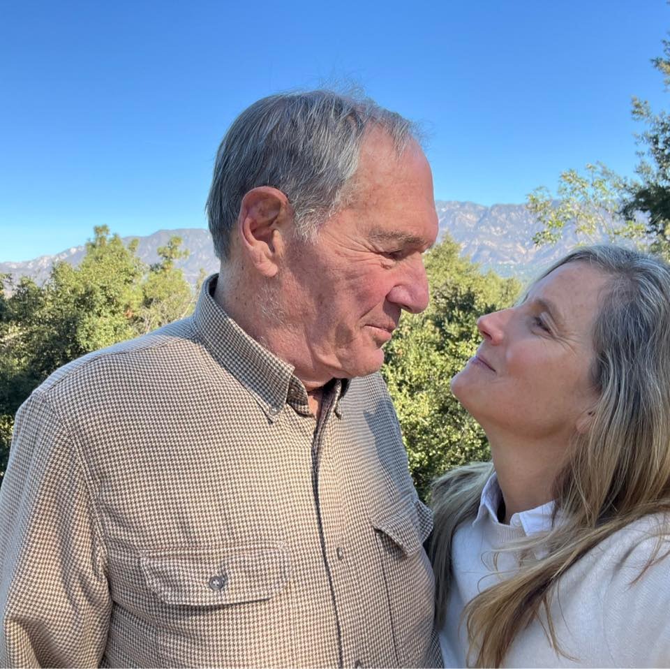 Andy and Shyla Stewart look lovingly at each other, mountains behind them.