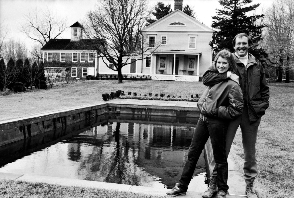 Andy and Martha in front of a pool and a house.