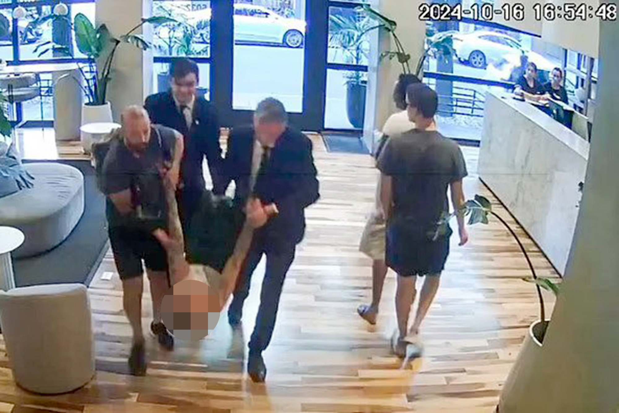 Liam Payne carried through hotel by three men.