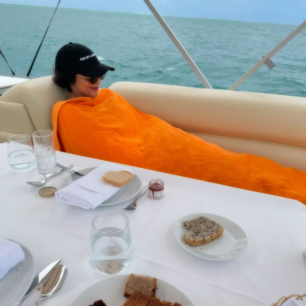 Jameela Jamil keeps warm under a blanket at breakfast.