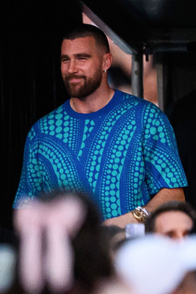 Travis Kelce wearing a blue shirt as he sits in the audience at Taylor Swift's show