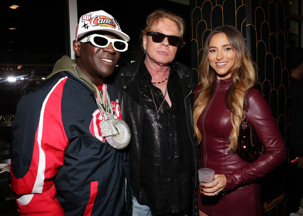 Flavor Flav, Axl Rose, and Sophia Graves posing for a photo at the F1 Las Vegas event hosted by Raising Cane's Owner and Founder, Todd Graves