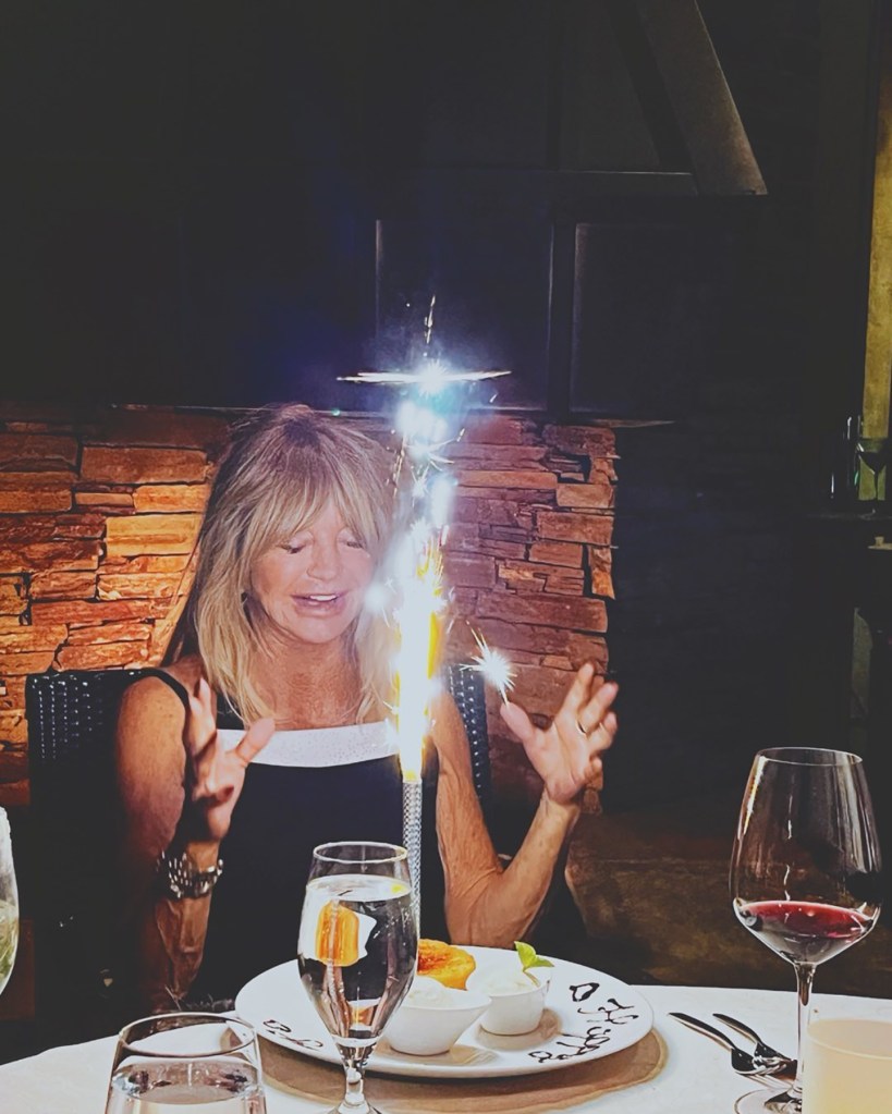 Goldie Hawn sitting at a table with a sparkler