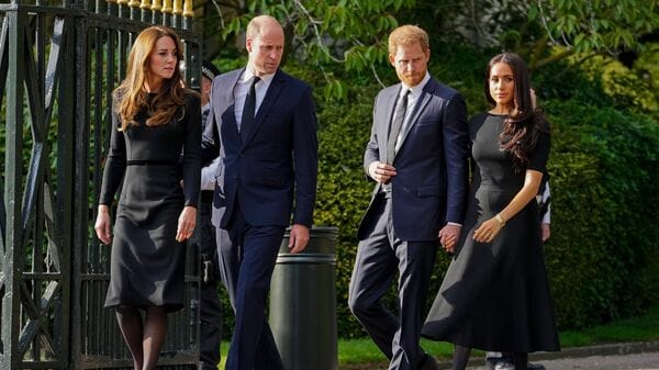 FILE - Britain's Prince William, second left, Kate, Princess of Wales, left, Britain's Prince Harry, second right, and Meghan, Duchess of Sussex view the floral tributes for the late Queen Elizabeth II outside Windsor Castle, in Windsor, England on Sept. 10, 2022. (AP Photo/Martin Meissner, File)