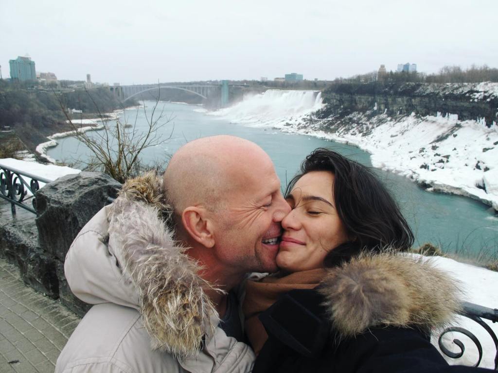 Bruce Willis and his wife, Emma Heming, kissing.