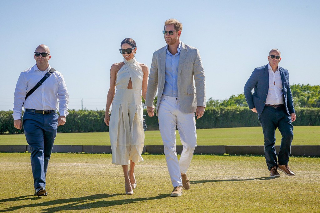 Prince Harry and Meghan Markle walk side by side on a polo field