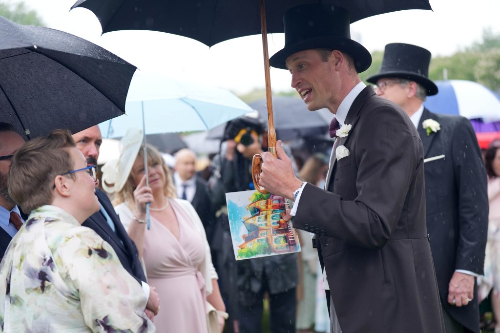 Prince William holds an umbrella.