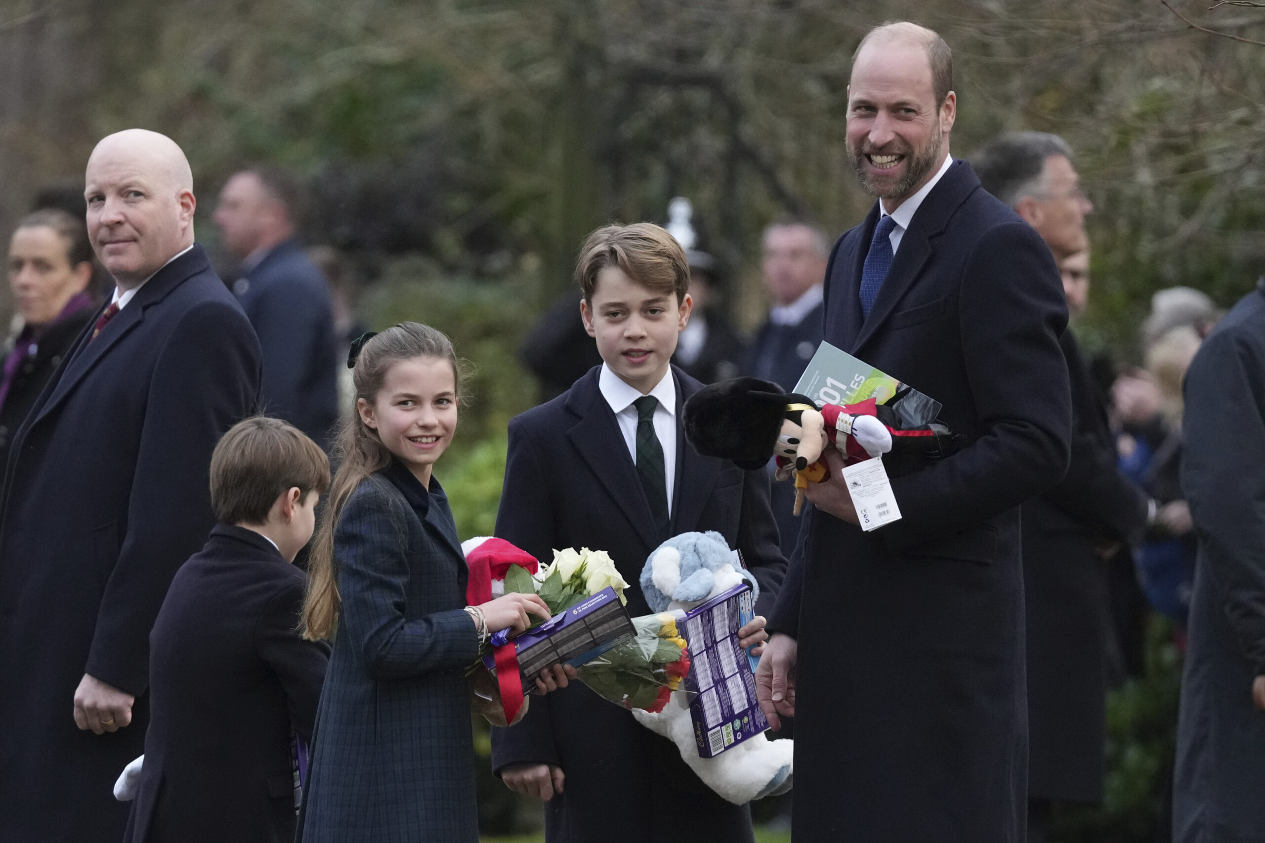 Prince William, right, with his children Prince George, Princess Charlotte and Prince Louis hold a collection of gifts given by well-wishers after they attended the Christmas day service at St Mary Magdalene Church in Sandringham in Norfolk, England.