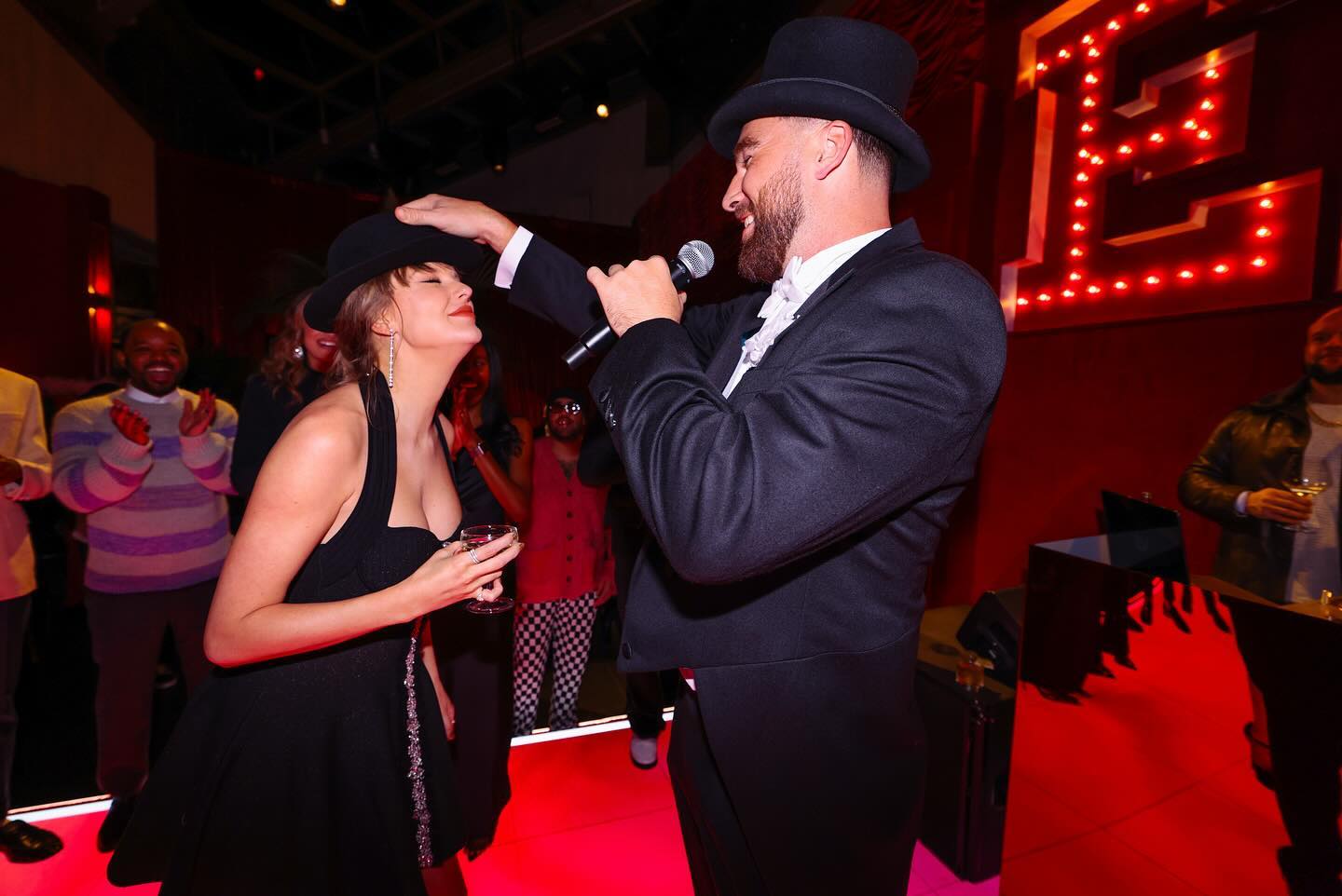 Travis Kelce giving Taylor Swift the "22" hat at the Eras tour wrap party.