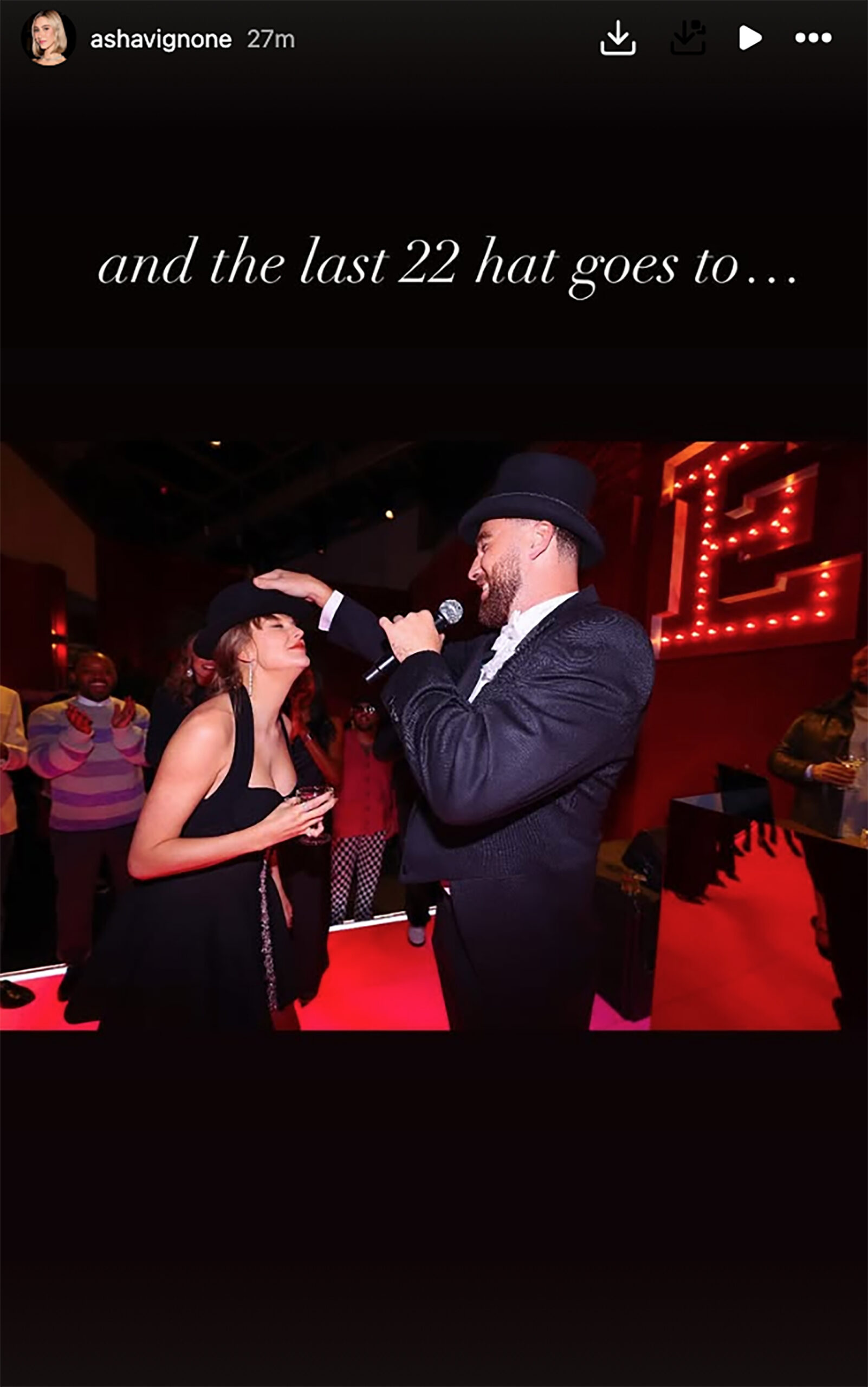 Travis Kelce giving Taylor Swift the "22" hat at the Eras tour wrap party.