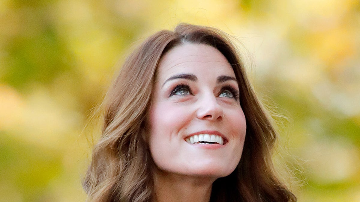 Kate Middleton wearing a blue dress smiling and looking up.