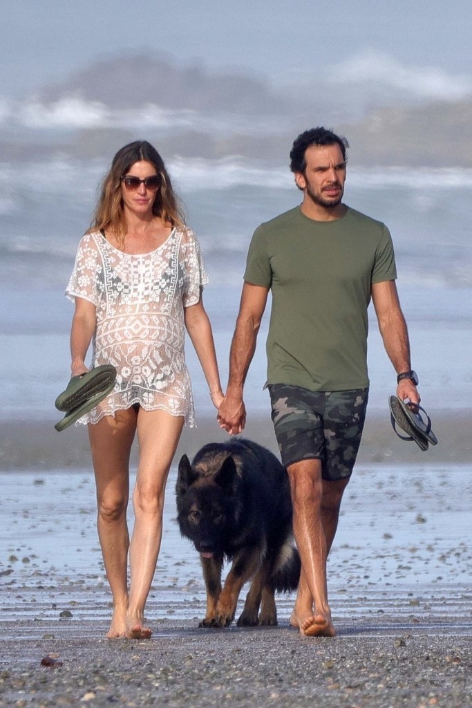 Gisele Bündchen and Joaquim Valente walking on a beach.