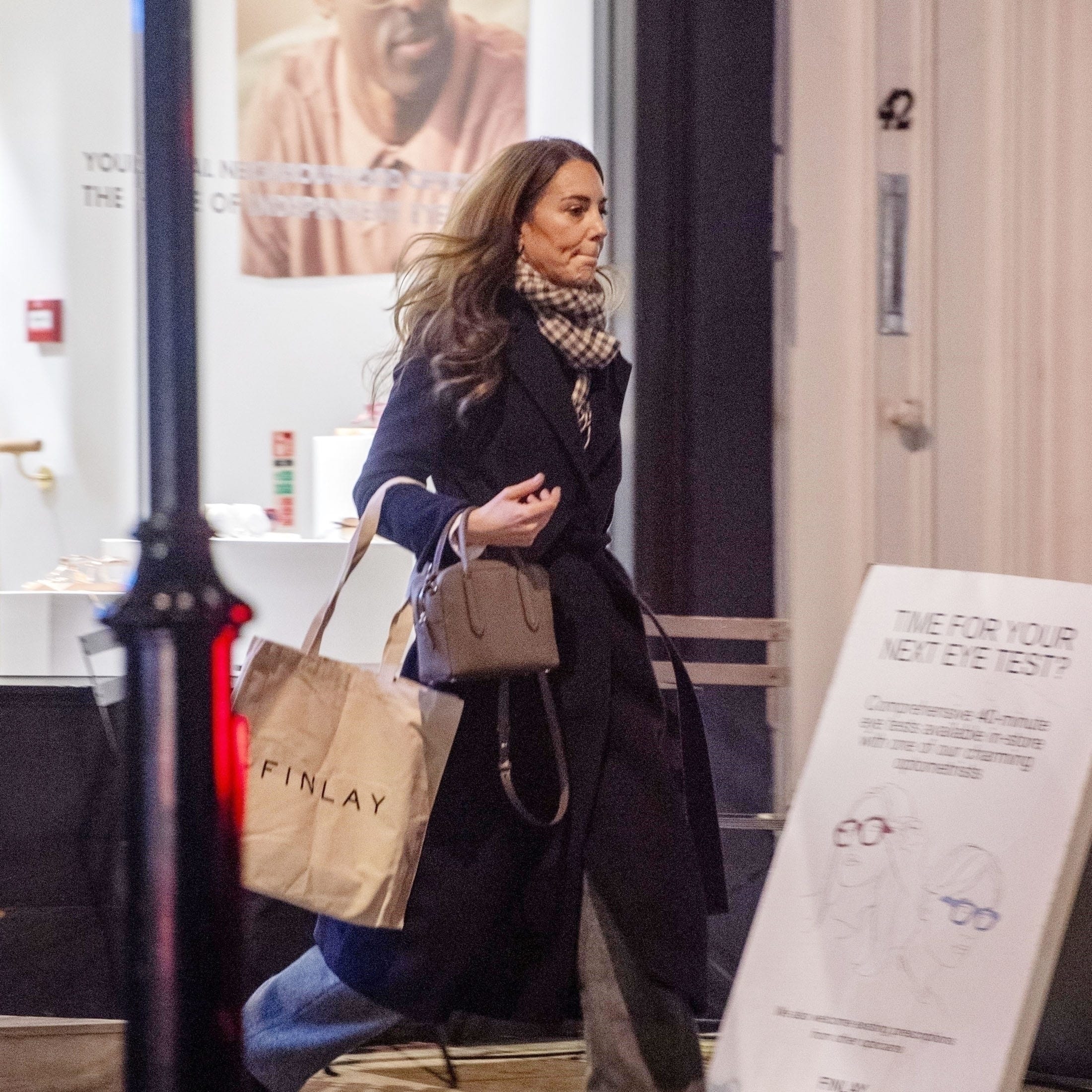 A person walking past a store carrying shopping bags.