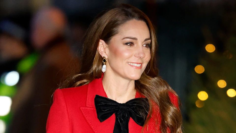 Princess Kate wearing read coat and black ribbon at Christmas Carol