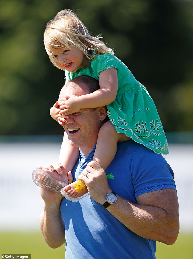 The young royal smiling and covering her father's eyes as she is carried on his shoulders in 2016