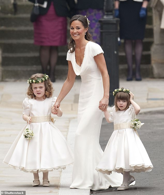 Pippa holding the hands of two flower girls, Grace Van Cutsem and Eliza Lopes, at her sister's wedding