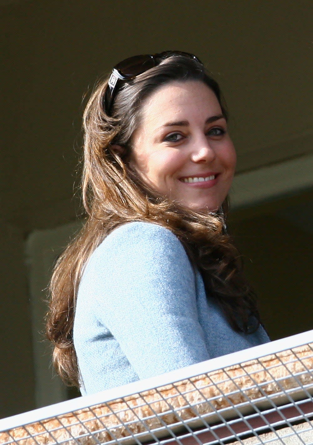 Kate Middleton smiling wearing a light blue sweater.