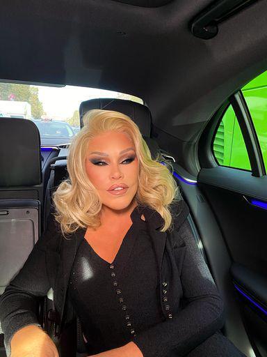 Jocelyn Wildenstein in a black suit in the back of a car.