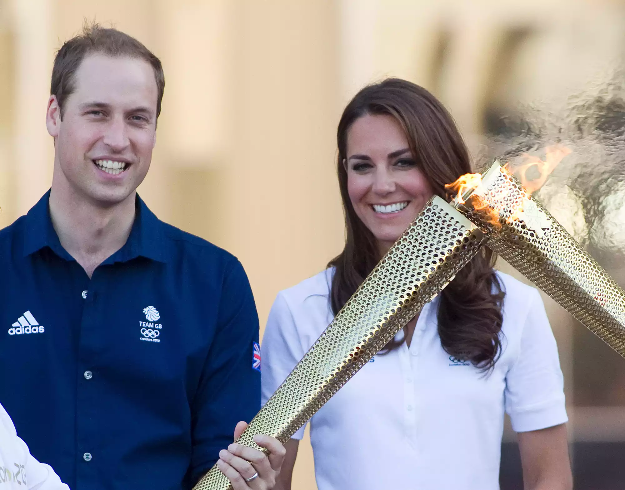 Prince William, Duke of Cambridge and Catherine, Duchess of Cambridge watch as torchbearer Wai Ming passes the Olympic Torch to John Hulse at Buckingham Palace on it's route around Britain to the Olympic Stadium on July 26, 2012 in London, England