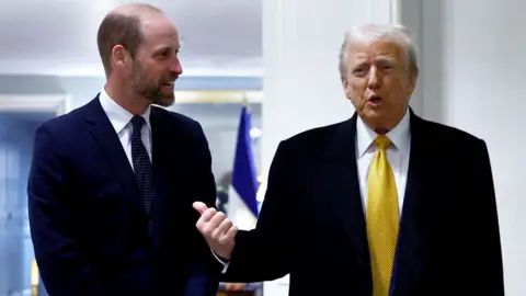 Reuters Prince William, dressed in a dark suit and tie, speaks with Donald Trump, who wears a dark suit, white shirt, and yellow tie.