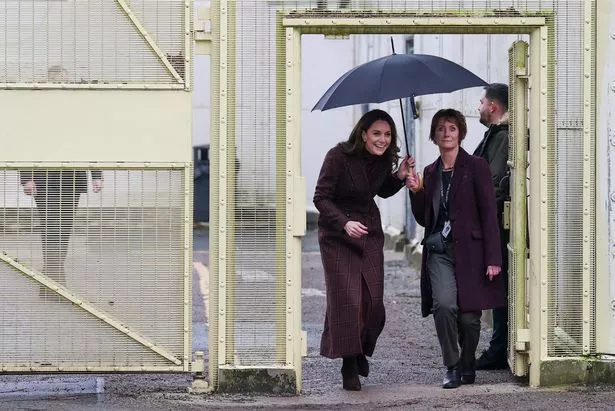 Kate manouvres through the prison gates with her umbrella