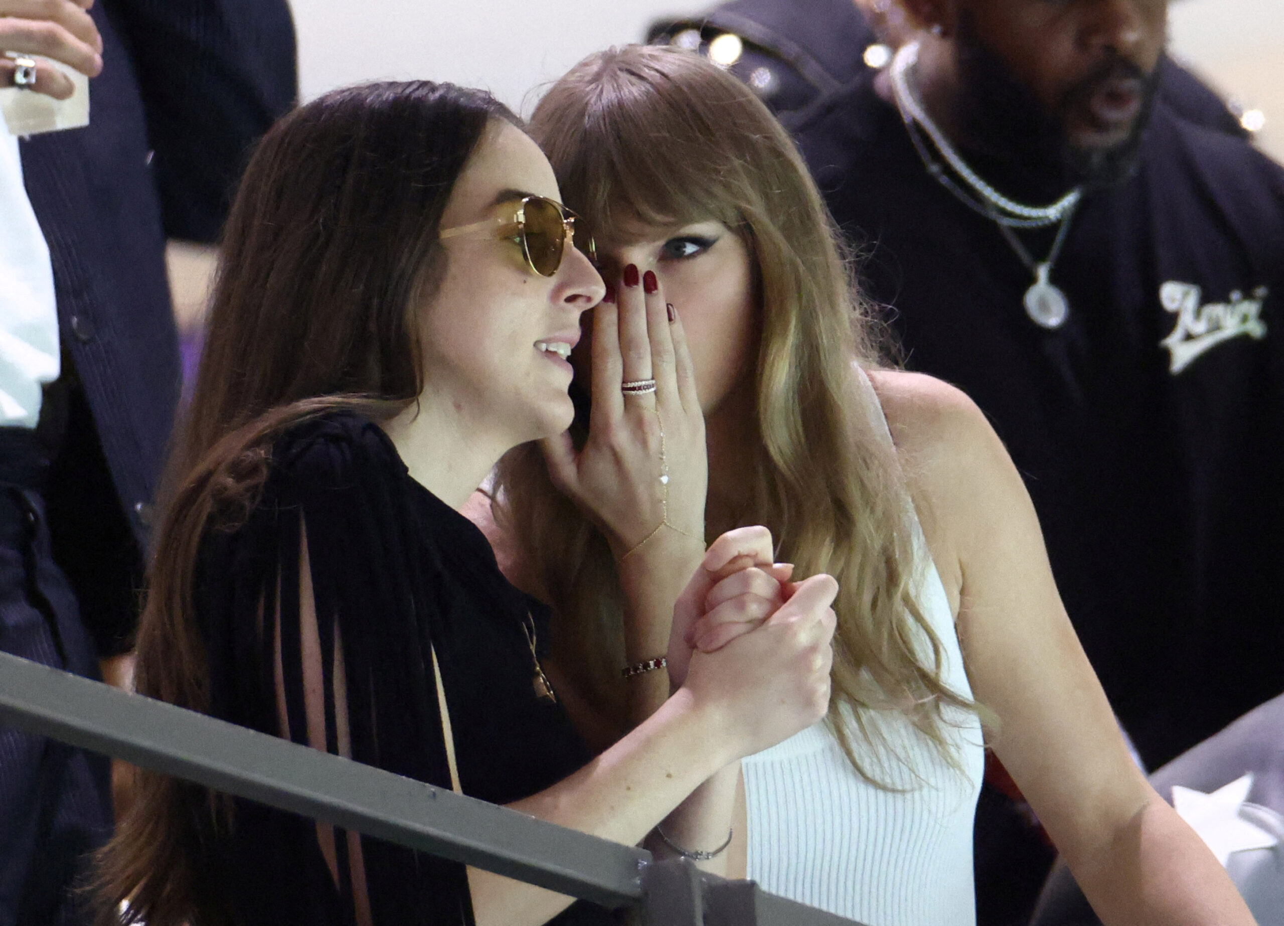 Taylor Swift whispering to a friend