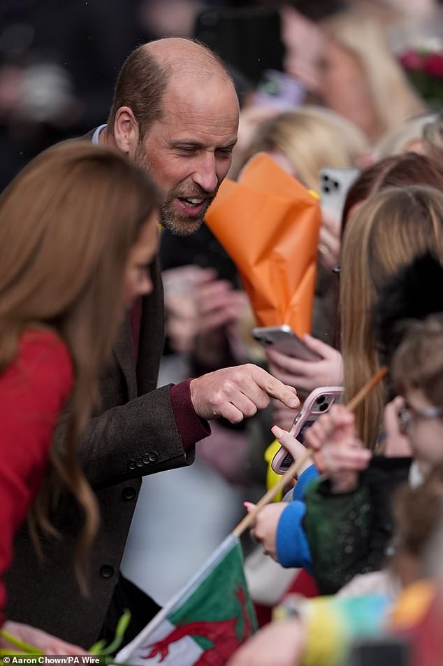 William appeared to be pointing at something on a fan's phone as he and Kate enjoyed their visit today