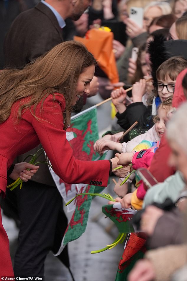 Kate leaned down to speak with children - who were holding out daffodils and Welsh flags - this afternoon